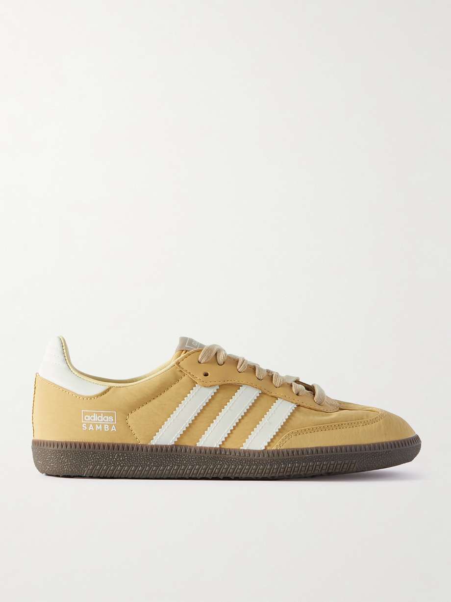 adidas Originals' 'Samba OG' leather trimmed shell sneakers in yellow with white stripes. Debuted in the '50s as a low-profile soccer style - today you'll spot them off the field worn with everything from dresses to tailored pants. This pair is made from vibrant yellow shell trimmed with leather, and subtly detailed with the brand's signature three stripes.