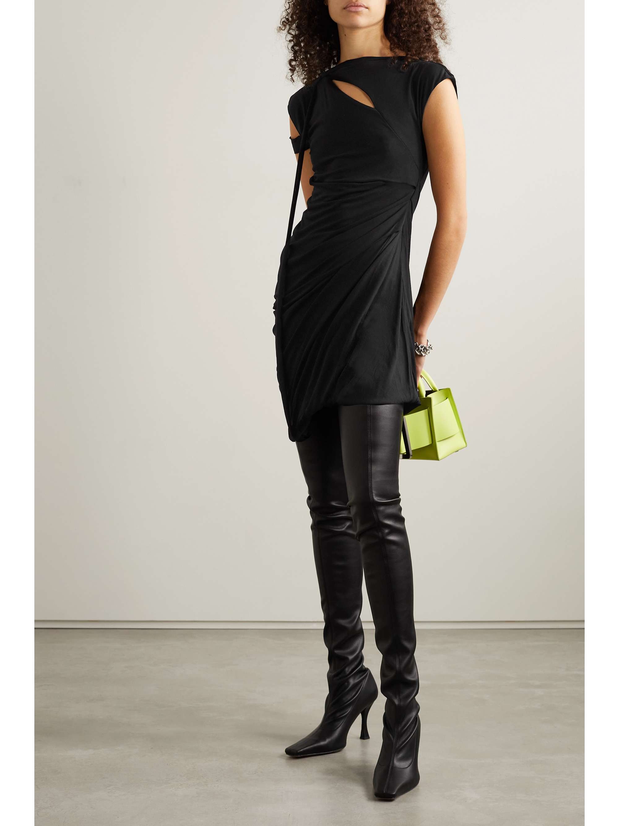 Black mini dress strategically ruched and draped for a flattering fit. It's made from soft jersey and has small cutouts at the chest and shoulder.