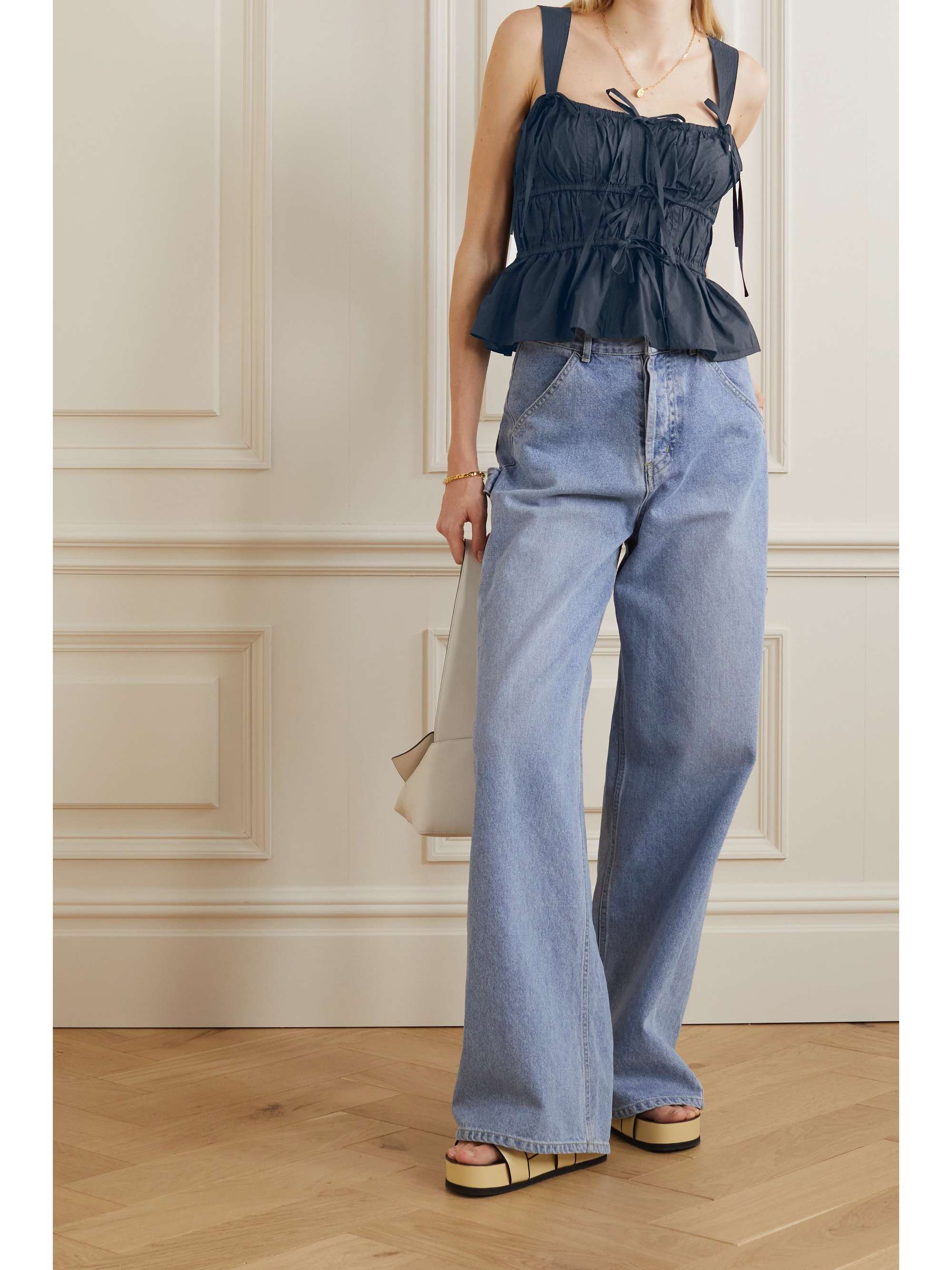 Sleevless black cotton poplin top with wide straps and sweet ties that accentuate the gathered finish and subtle peplum hem. It is lightly boned along the sides for added structure and support. 