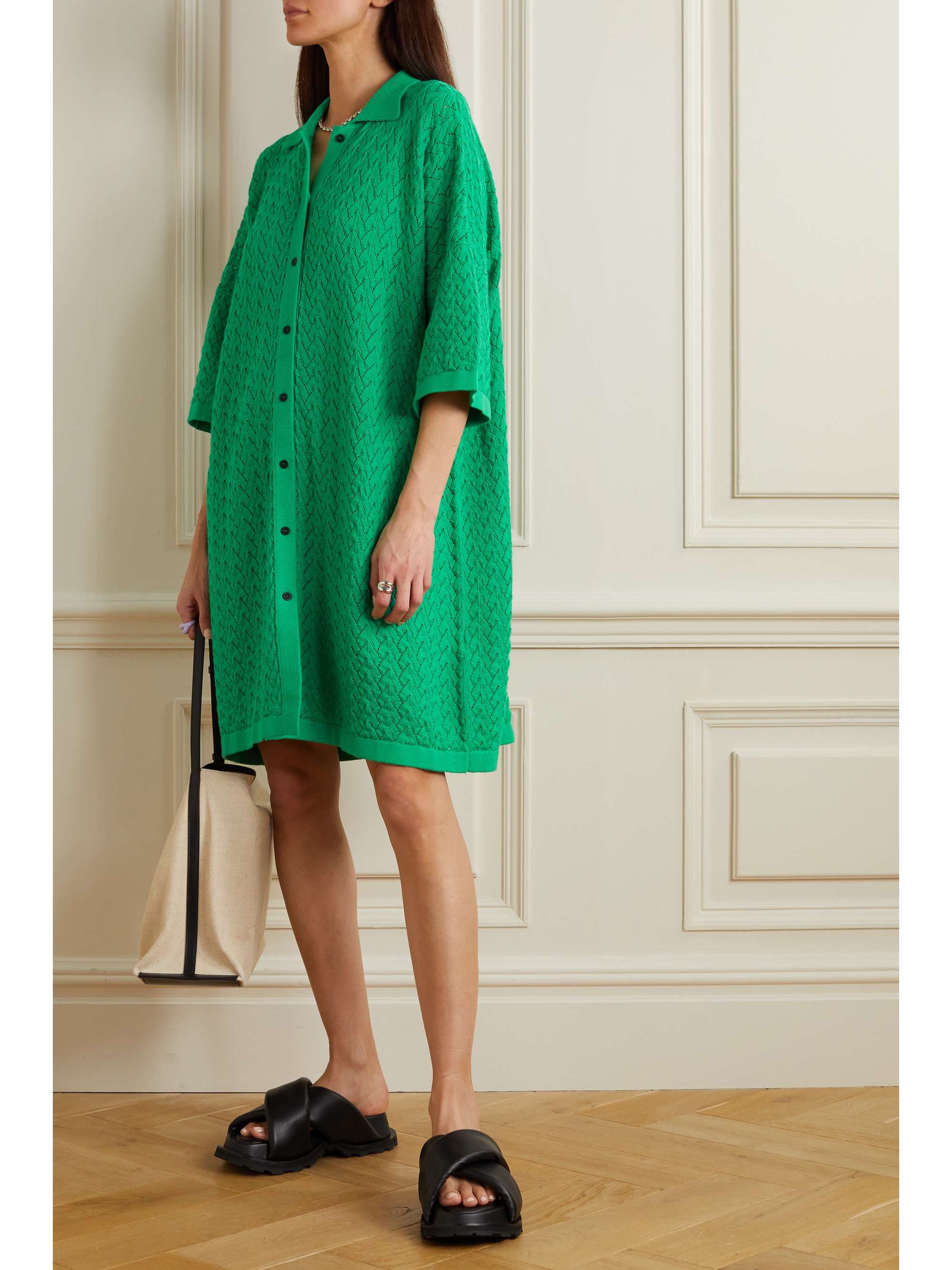 green shirt dress knitted from soft cotton in an airy pointelle stitch, so it's breathable and light enough for warmer weather. It has a loose fit reaching to the knees with dropped shoulders and a neat collar and button down front.