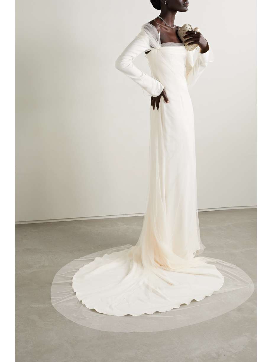 Danielle Frankel's 'Leona' gown is made from figure-skimming cady that's overlaid with frothy tulle, giving it beautiful texture and dimension. It has a cold-shoulder neckline with gathered details and slim grosgrain straps to keep it in place. The train trains elegantly behind as you walk. Wear it with a diamond-encrusted choker on the big day.